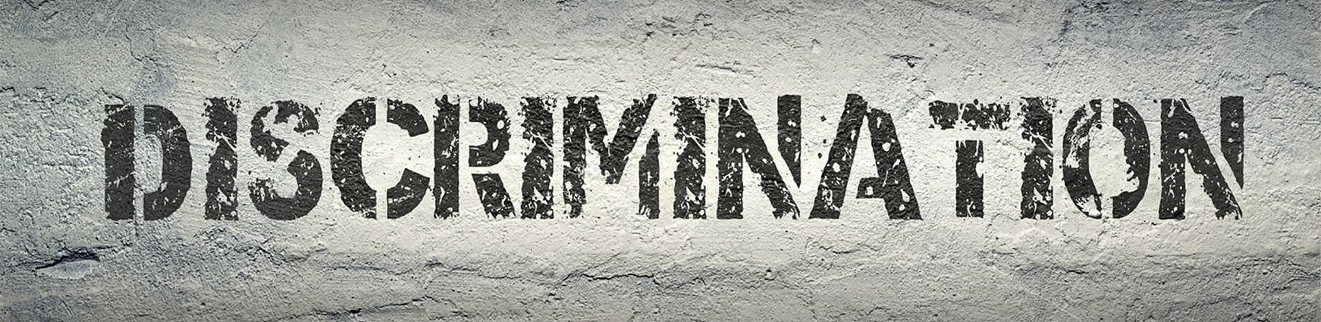 The word "discrimination" is stenciled in bold, textured black letters on a rough, gray concrete wall—a powerful statement highlighting the challenges a Los Angeles employment attorney might face in advocating for workplace fairness.
