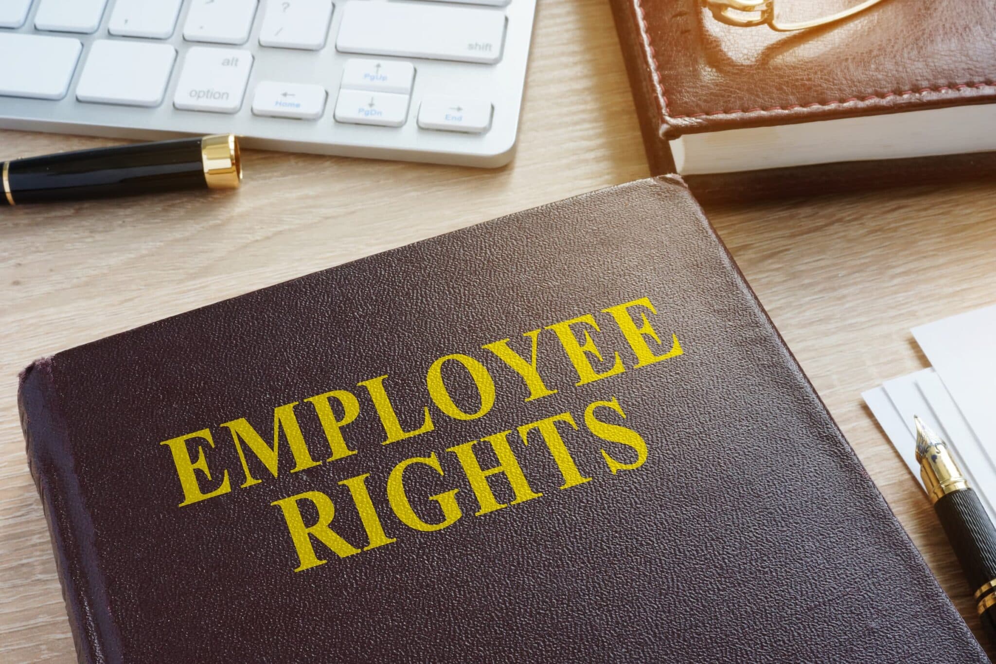 A book titled "Employee Rights" sits on a desk with a keyboard and a pen nearby, reflecting the expertise of an employment lawyer in Los Angeles. Employee Rights