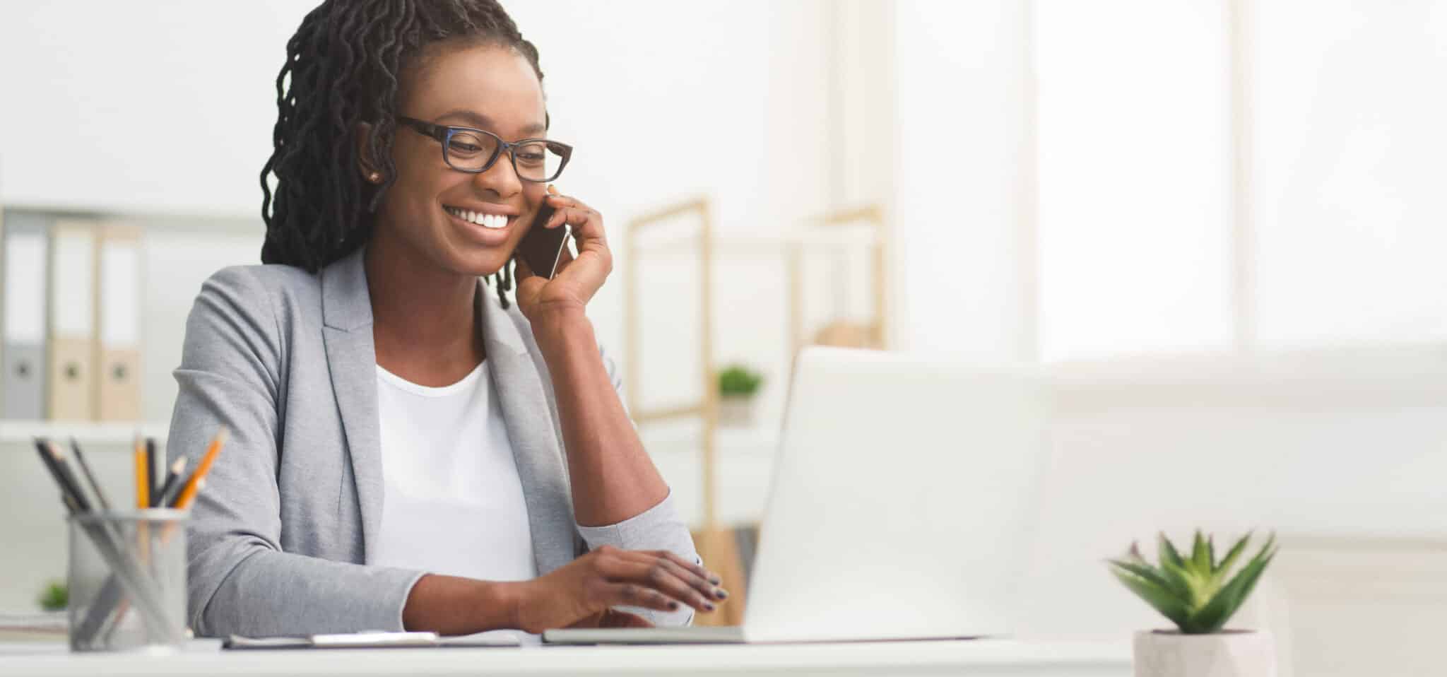 A woman in a gray blazer, possibly an employment lawyer in Los Angeles, is talking on the phone and working on a laptop at her desk. Employee Rights>Workplace Discrimination