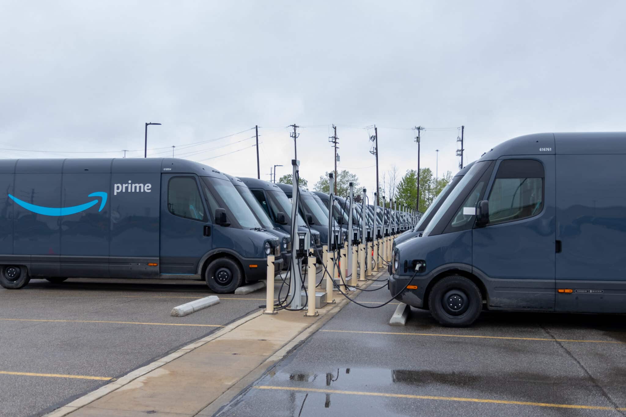 Electric delivery vans are parked in a lot, connected to charging stations in two neat rows, exemplifying Los Angeles' commitment to consumer protection and green initiatives. Employee Rights
